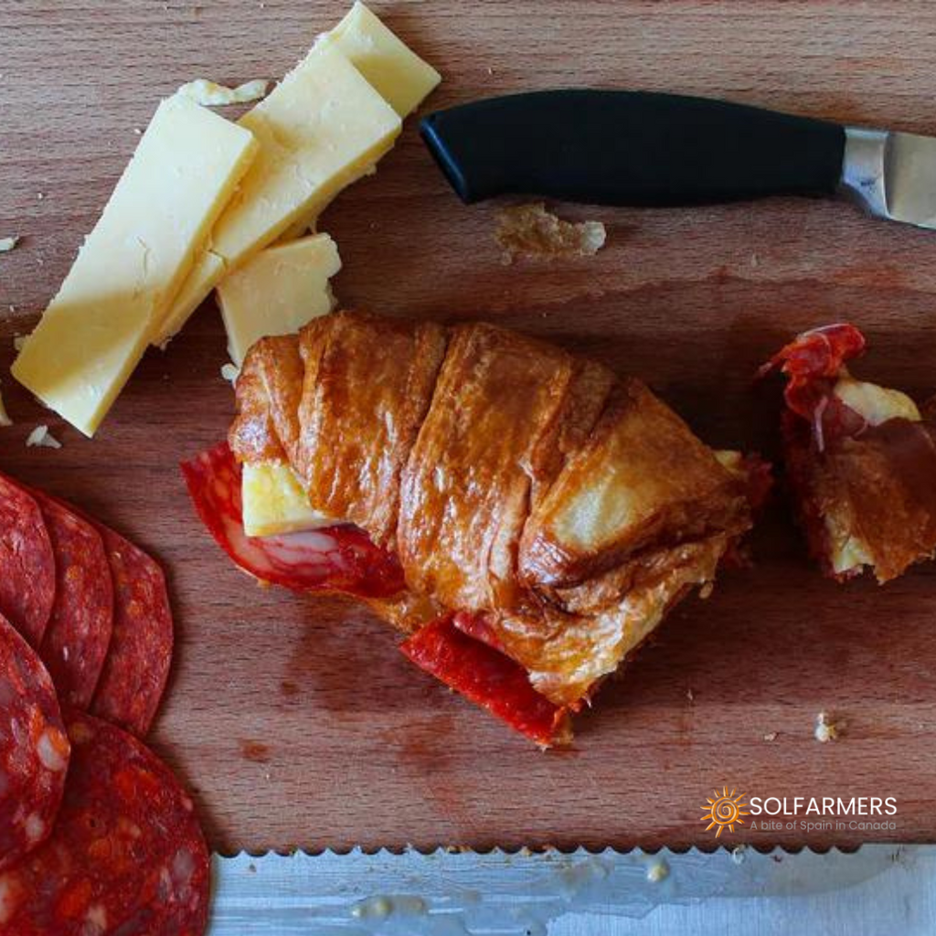 Bocadillo de chorizo gourmet servido en un croissant recién horneado, con el chorizo perfectamente dorado y jugoso, y el croissant crujiente por fuera y suave por dentro. Ideal para una comida rápida pero deliciosa