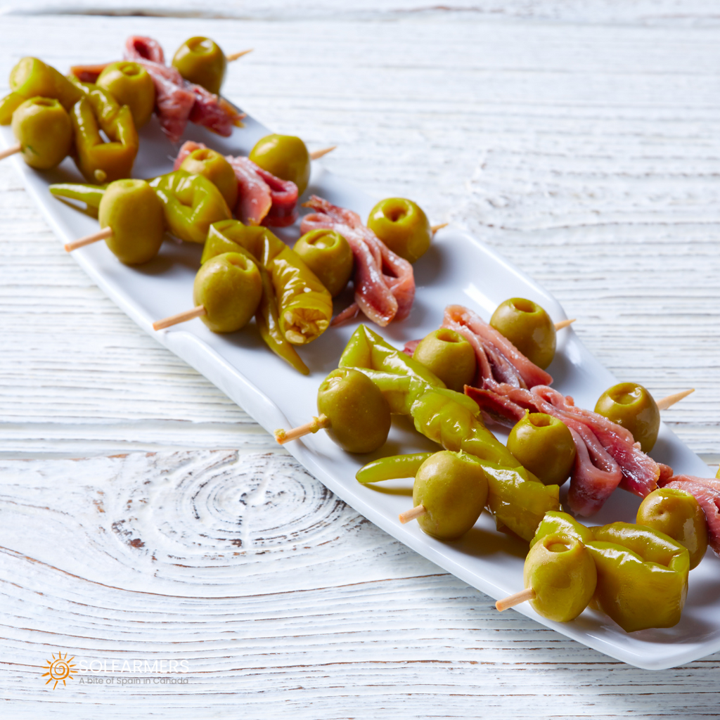 Pinchos de Gildas: Aceitunas verdes, guindillas en vinagre y anchoas, todo ensartado en un palillo para ofrecer un sabor intenso y equilibrado. Perfecto para una reunión informal o como tapa para disfrutar con una bebida.