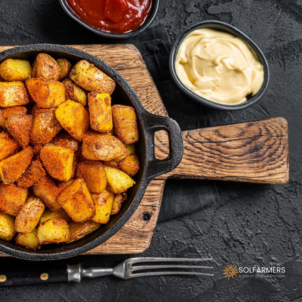 Patatas bravas: pieces of crispy french fries served on a plate with spicy red brava sauce and white aioli sauce, garnished with fresh parsley and paprika.